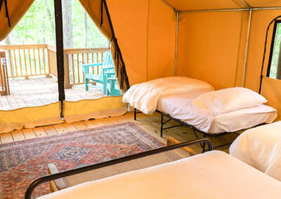 glamping tent interior with beds cozy decor forest view deck seating luxurious outdoor camping experience
