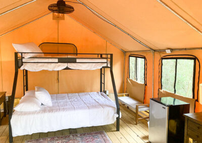 modern glamping tent interior with bunk beds mini fridge wood flooring cozy rustic camping