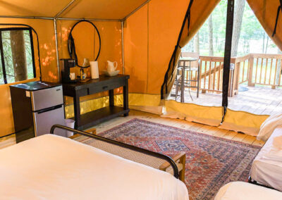 glamping tent interior with bed mini fridge and wooden deck overlooking forest perfect for luxury outdoor stays