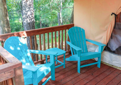 rustic deck with blue adirondack chairs glamping tent scenic forest view
