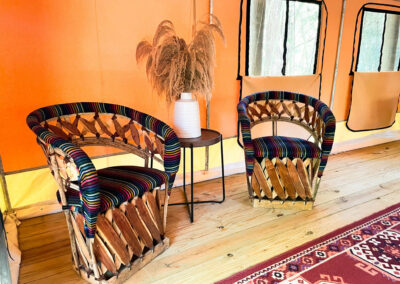 boho seating area with colorful wicker chairs pampas grass wooden flooring and patterned rug in bright glamping tent