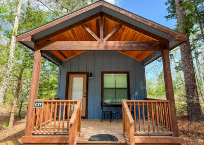 wooden cabin exterior with porch amidst forest trees clear blue sky outdoor retreat rustic home peaceful nature setting