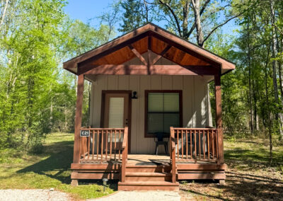 small rustic cabin in wooded area front porch surrounded by lush greenery outdoor retreat peaceful nature escape