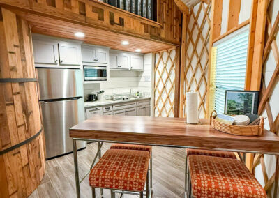 modern yurt interior with loft kitchen dining table stools features wood accents high ceilings and natural light