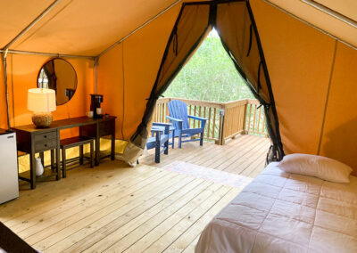 luxury glamping tent with cozy bed desk and seating on deck surrounded by nature ideal for unique outdoor getaways