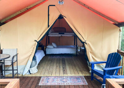 glamping tent interior with beds wooden flooring outdoor seating luxury camping setup