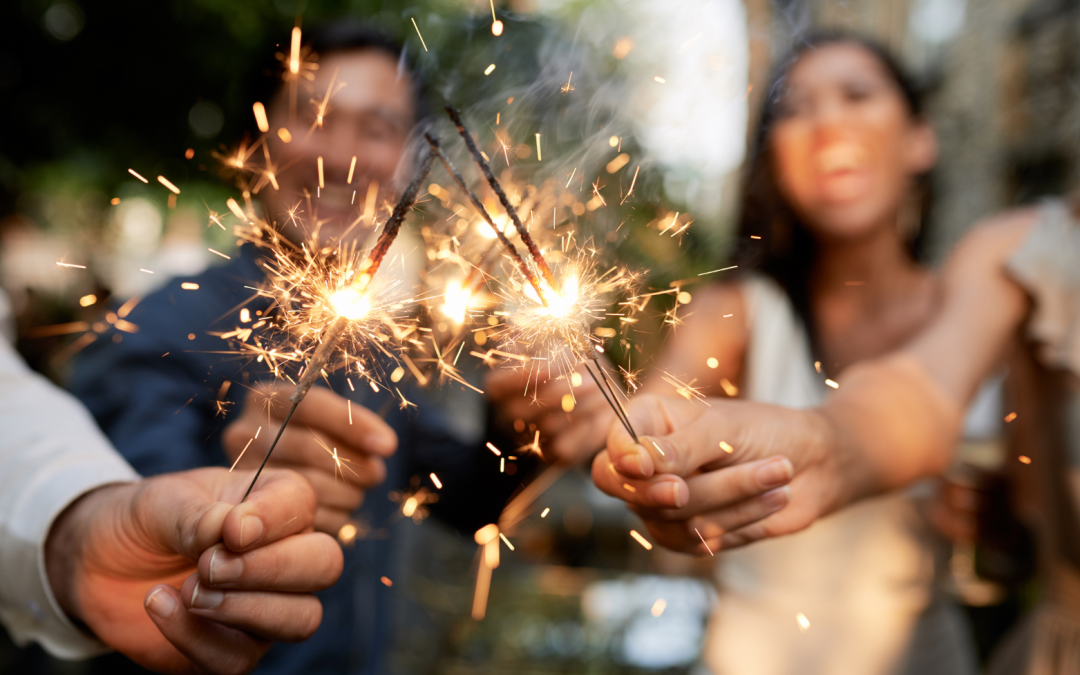 Friends celebrating with sparklers outdoors at a joyful evening gathering.
