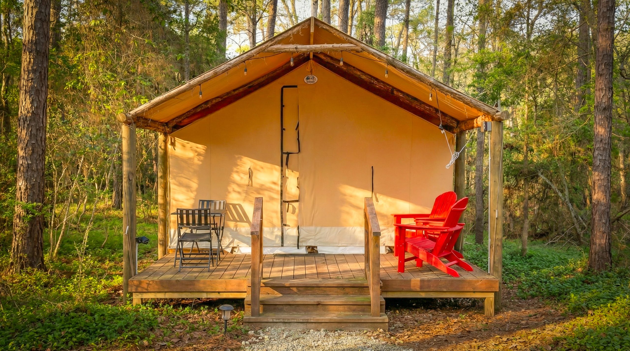 Canvas glamping tent with a covered wooden deck and red chairs Canvas glamping tent with a covered wooden deck and red chairs